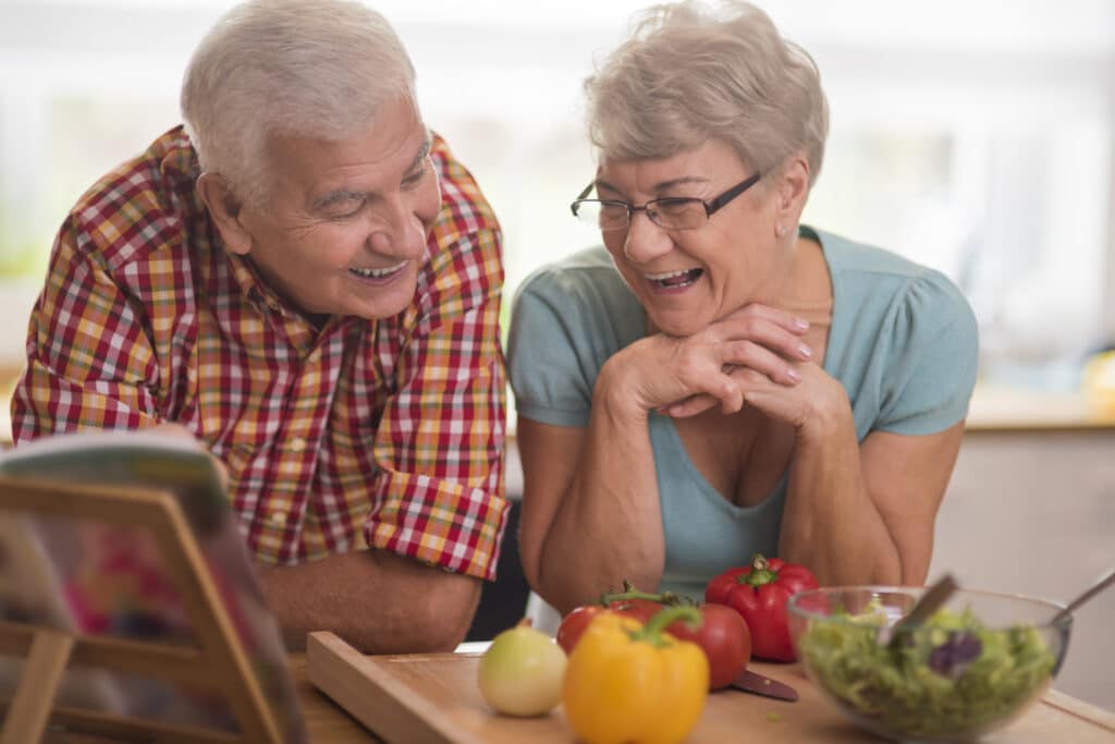 saude-do-idoso-casal-apoiado-na-bancada-da-cozinha-com-legumes-e-verduras